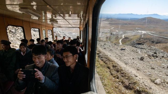 In a photo taken on September 11, 2019, North Korean visitors ride a funicular railway to a viewing platform near the summit of Mount Paektu, near Samjiyon. - Mount Paektu has long been considered the spiritual birthplace of the Korean nation and is a place of pilgrimage for tens of thousands of North Koreans every year, who are trained from birth to revere their leaders. Every year 100,000 North Koreans or more are taken on study tours to the camp, the mountain, and nearby revolutionary sites where relics of operations are preserved. Dressing in khaki uniforms said to resemble guerrillas' outfits and carrying red flags, they march to the summit of the volcano. (Photo by Ed JONES / AFP) / To go with AFP story NKorea-politics-social-Paektu, FOCUS by Sebastien Berger