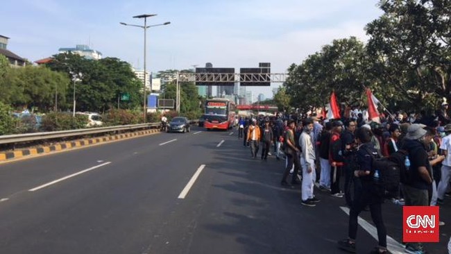 Massa duduk di dua lajur di jalan tol sehingga membuat lalu lintas tersendat. Massa tak mengindahkan imbauan polisi untuk tak duduk di jalan tol.