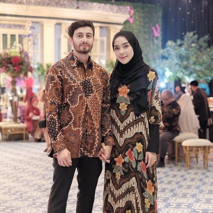 <p>Adapun selebgram Hamidah Rachmayanti dan suami kompak mengenakan batik dalam dalam sebuah acara pernikahan. Hamidah memadukan long dress batik dengan hijab berwarna hitam. (Foto: Instagram @hamidahrachmayanti)</p>