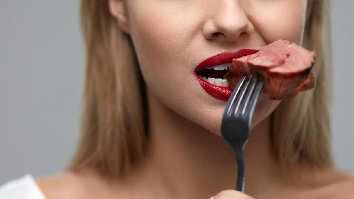 Woman Eating Meat. Closeup of Healthy Hungry Girl With Beautiful Face, Red Lips Eats Delicious Grilled Meat. Female Mouth Biting Piece Of Tasty Beef Steak On Fork. Nutrition Concept. High Resolution