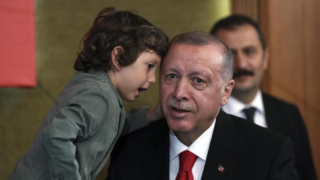 Turkey's President Recep Tayyip Erdogan, listens to a boy during an event in Ankara, Turkey, Saturday, Oct. 5, 2019. Turkey's president threatened Saturday to launch a solo military operation into northeastern Syria, where U.S. troops are deployed and have been trying to defuse tension between its NATO ally and Syrian Kurdish forces. (Presidential Press Service via AP, Pool)