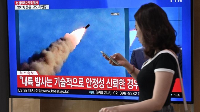 A woman walks past a television news screen showing file footage of a North Korean missile launch, at a railway station in Seoul on September 10, 2019. - North Korea on September 10 fired projectiles toward the sea, South Korea's military said, hours after Pyongyang said it is willing to hold working-level talks with the United States in late September. (Photo by Jung Yeon-je / AFP)