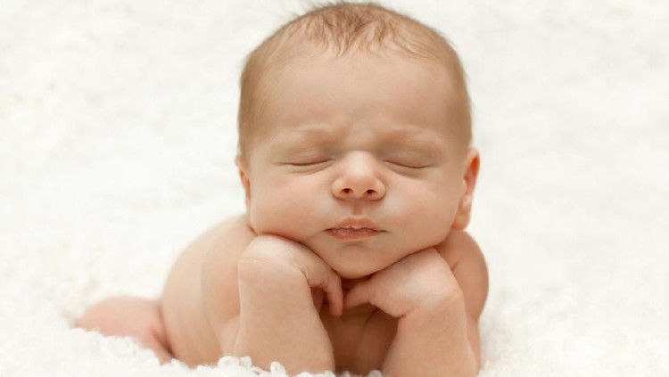 Adorable newborn propped up on own hands.