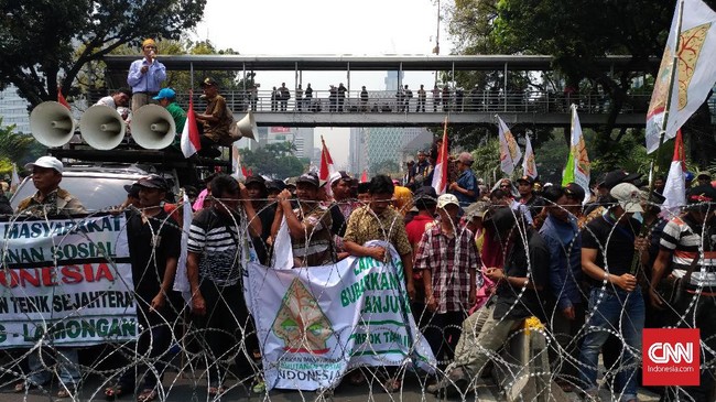 Ratusan petani yang hendak menggelar aksi unjuk rasa tertahan di Jalan Medan Merdeka Barat dan tak bisa menuju Istana Negara karena polisi menutup jalan.