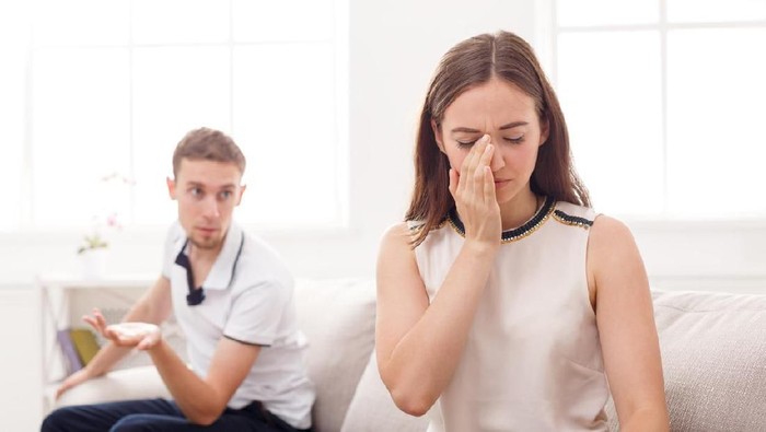 Couple conflict. Stressed crying female sitting on couch with abusive husband after quarrel, ready to divorce