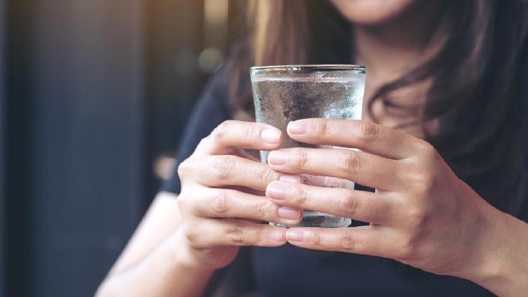 Closeup image of woman holding a glass of cold water to drink