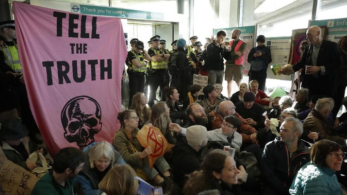 Police Officers stand guard as Extinction Rebellion demonstrators peacefully block an entrance at City Airport in London, Thursday, Oct. 10, 2019. Some hundreds of climate change activists are in London during a fourth day of world protests by the Extinction Rebellion movement to demand more urgent actions to counter global warming. (AP Photo/Matt Dunham)