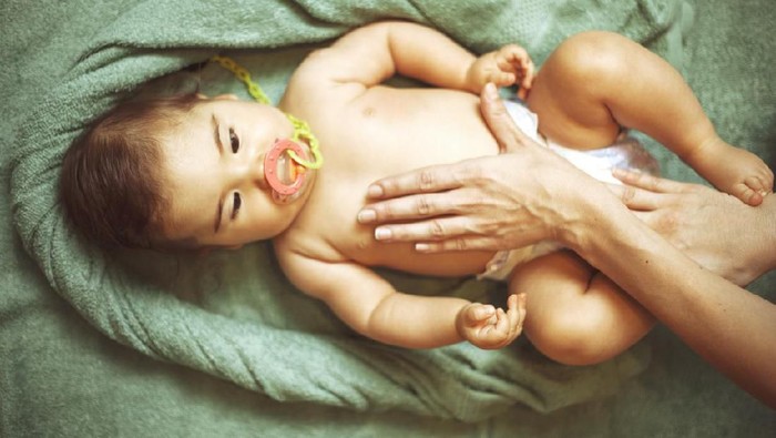 Mother massaging her little baby girl, shallow focus