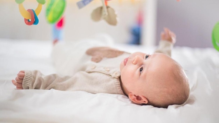 Happy baby playing in baby gym toy