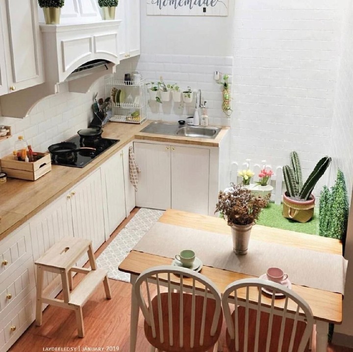 <p>Dominasi warna putih di dapur ini membuat ruangan terlihat lebih luas. Warna cokelat kayu pada meja, kursi, dan meja dapur nampak serasi dengan dinding dan lemari putih. Tambahan dekorasi taman buatan di sudut ruangan juga membuatnya terlihat segar nih, Bun. (Foto: Instagram @ladydeeledsy)</p>