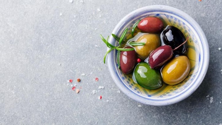 Olives assortment in bowl with oil. Top view. Copy space
