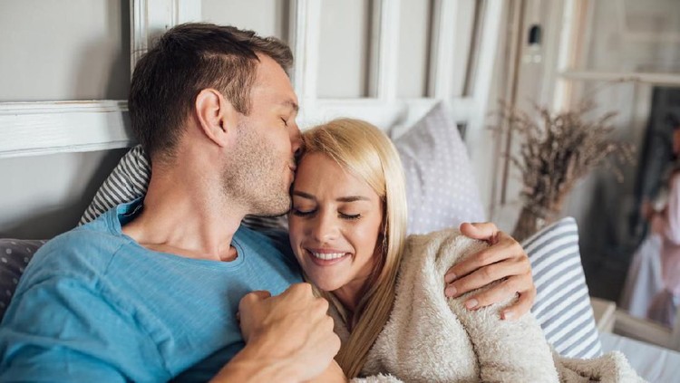 couple Happy young couple holding hands and kissing in bed