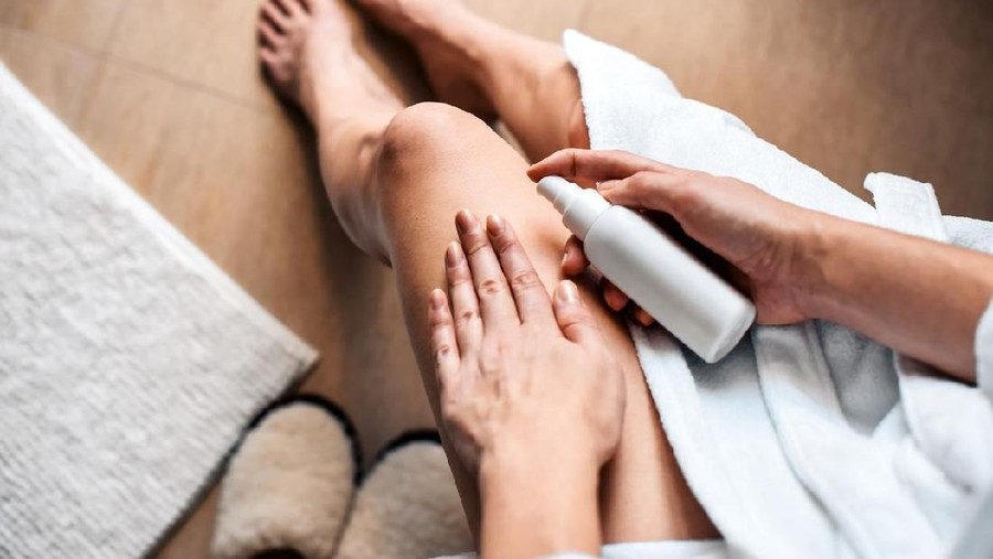 The girl in the bathroom puts anti-cellulite cream, serum on the legs and body. Body care concept.