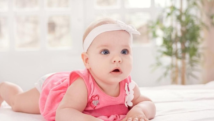 Adorable little baby with blue eyes on bed