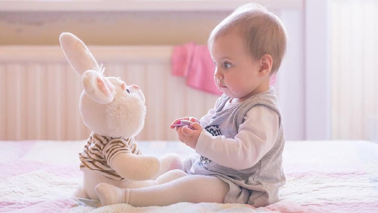 10 months old baby girl playing with plush rabbit