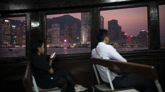 In this Oct. 10, 2019 photo, people ride in a ferry from Hong Kong Island to Kowloon as the sun sets in Hong Kong. The body-blow of months of political protests on Hong Kong’s tourism is verging on catastrophic for one of the world’s great destinations. Geared up to receive 65 million travelers a year, the city’s hotels, retailers, restaurants and other travel-oriented industries are suffering. But some intrepid visitors came specifically to see the protests and are reveling in deep discounts and unusually short lines at tourist hotspots. (AP Photo/Felipe Dana)