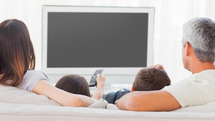 832080580 Family sitting on sofa watching television together at home
