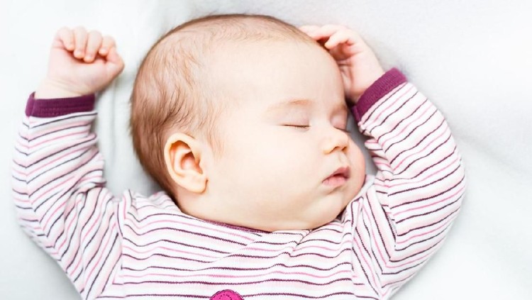 Portrait of a beautiful baby girl sleeping on white blanket in bed. Female newborn face closeup.