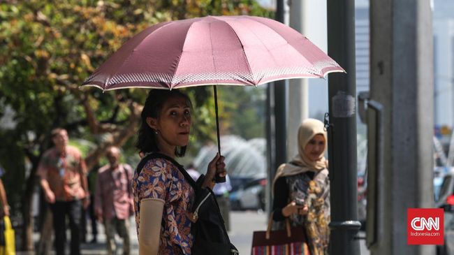 Warga Jakarta menggunakan payung menghalau sengatan matahari siang hari di kawasan Thamrin, Jakarta, Selasa, 22 Oktober 2019. BMKG mencatat suhu udara pada siang hari masih terjadi di sekitar wilayah Indonesia bagian selatan hingga akhir Oktober 2019. CNNIndomesia/Safir Makki