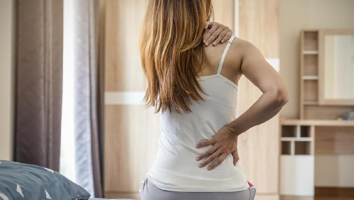 Woman suffering from back ache on the bed, healthcare and problem concept