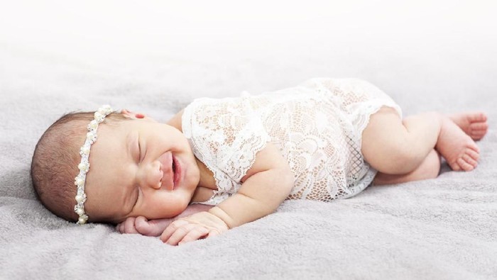 Little princess on a light blanket. Photo session of a newborn baby. Professional newborn photography.