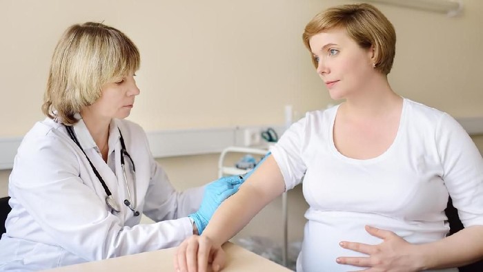 Doctor or paramedic makes vaccination to a pregnant woman. Medical insurance childbearing. Family doctor for gestation. Health care and medicine.