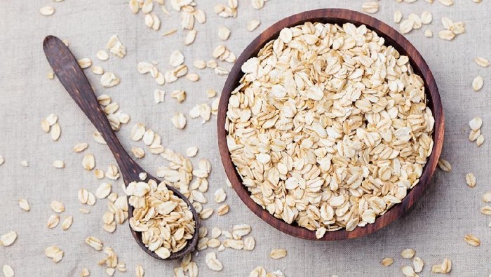 Healthy breakfast Organic oat flakes in a wooden bowl Grey textile background Top view Copy space