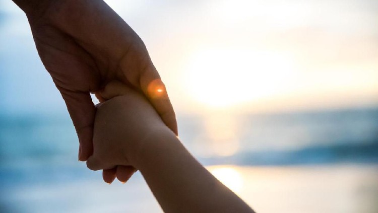 soft focus parent hold the little child hand during sunset, warm tone.