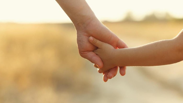 soft focus parent hold the little child hand during sunset, warm tone.