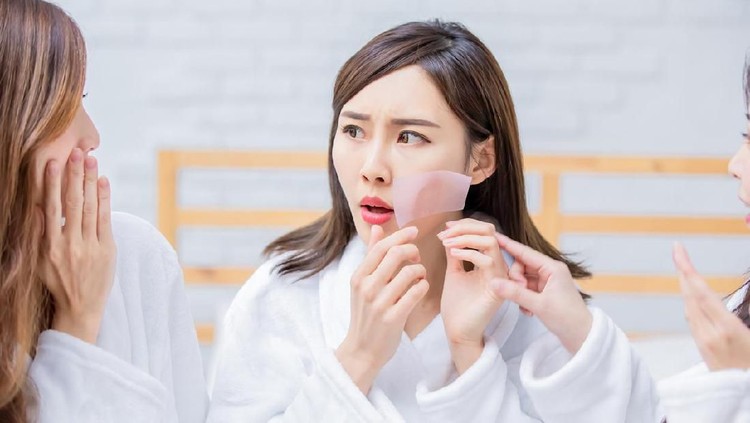 asian women put the oil absorbing paper on her face and feel bad