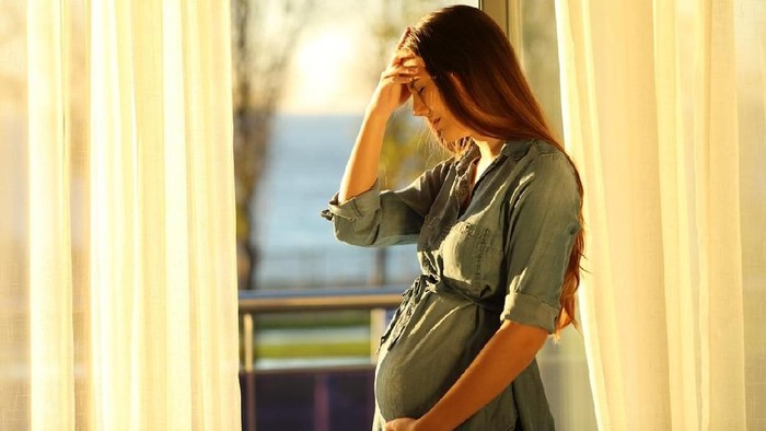 Worried pregnant woman complaining at home