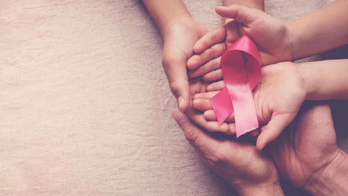 Family hands holding pink ribbon, breast cancer awareness, October pink concept