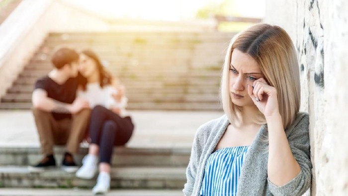Lonely single girl feeling depressed because of a happy couple laughing on the next staircase.