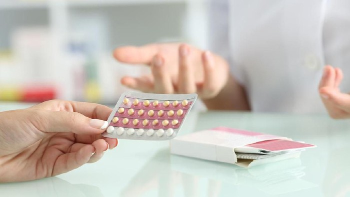 Oral contraceptive pill on pharmacy counter with colorful pills strips background.