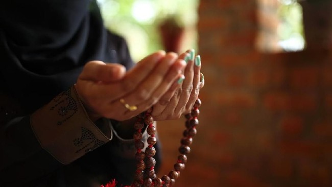 Close-up shot of a Muslim woman's hands holding rosary.