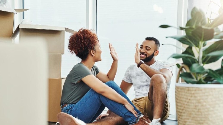 Shot of a young couple giving each other a high five while moving house