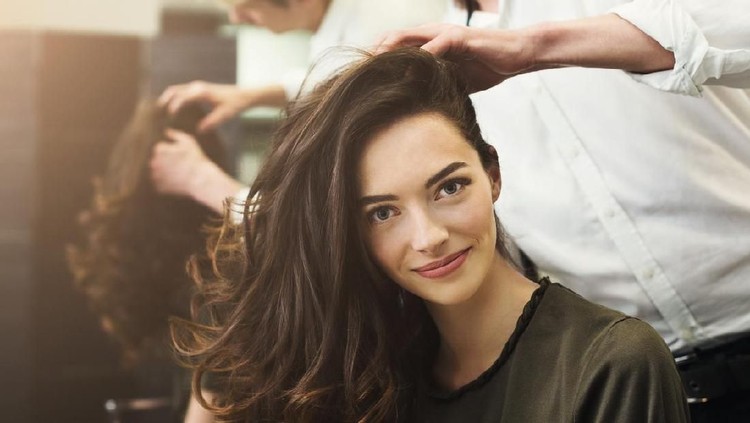 Happy woman sitting at beauty salon, making beautiful evening hairstyle with curls, copy space