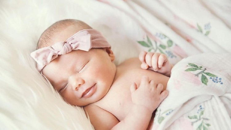 bayi perempuan Charming beautiful lovely small female baby with plump cheeks creeps on bed, looks innocently on something, being naughty. Cute baby infant plays alone. Newborn kid crawls. Enthusiastic child