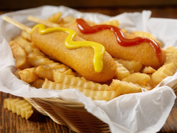 American finger food: corn dogs served with mustard at an outdoor picnic.