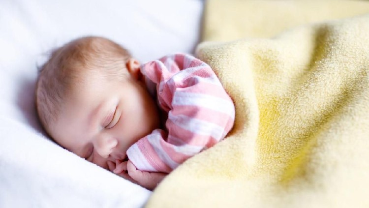 nama bayi laki-laki Sweet newborn baby sleeps in a basket. Beautiful newborn boy with bear toy.