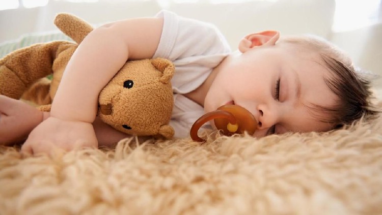 Sweet newborn baby sleeps in a basket. Beautiful newborn boy with bear toy.