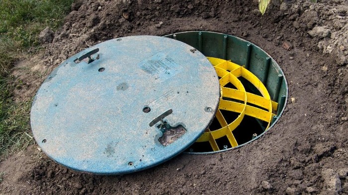 The partially removed plastic cover of a septic tank with the safety cover visible.