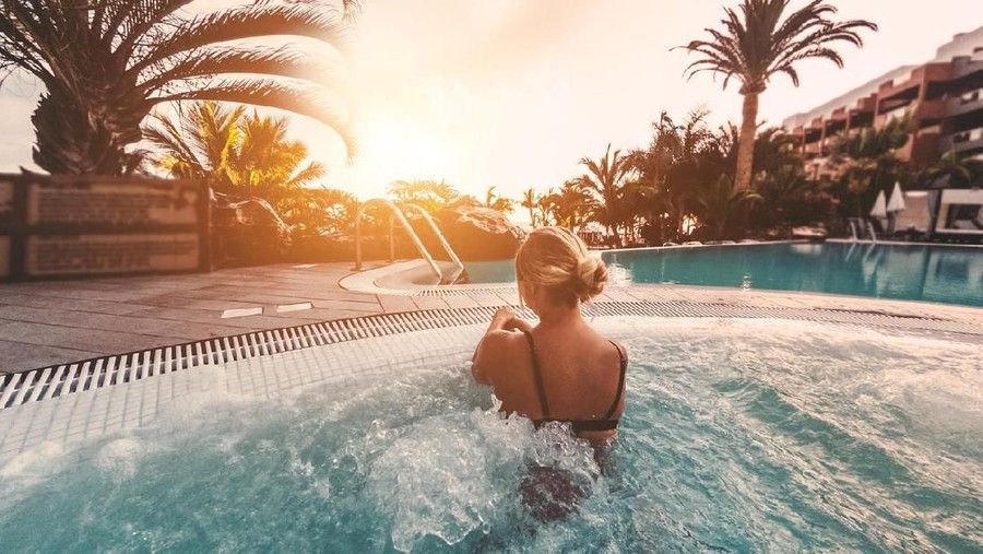 Young influencer woman relaxing inside hot tub at sunset outdoor - Girl enjoying summer vacation in a tropical destination - Travel&comma; new jobs trends and holiday concept - Soft focus on her body