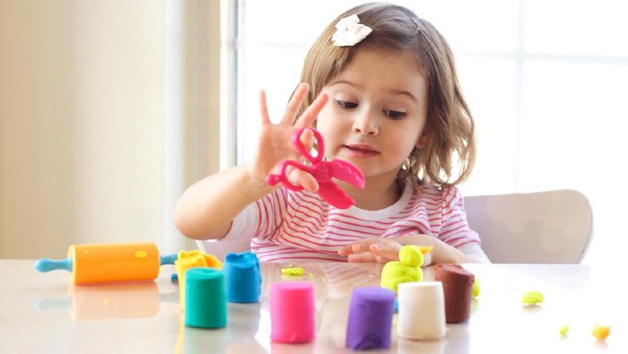 Young mom and her baby boy (2 years) at home playing with modeling clay dough.