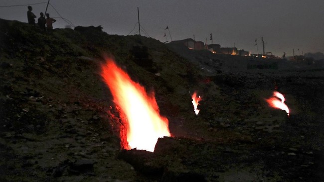 In this Oct. 23, 2019, photo, flames billow out of the fissures on the ground above coal mines in the village of Liloripathra in Jharia, a remote corner of eastern Jharkhand state, India. The fires started in 1916. More than a century later, they are still spewing flames and clouds of poisonous fumes into the air, forcing residents to brave sizzling temperatures, deadly sinkholes and toxic gases. (AP Photo/Aijaz Rahi)