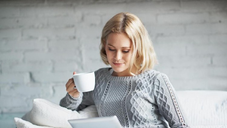 Woman sitting at a cafe working on digital tablet. Businesswoman sitting at cafe counter with a coffee using tablet computer.