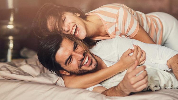 Happy young playful couple in bed.
