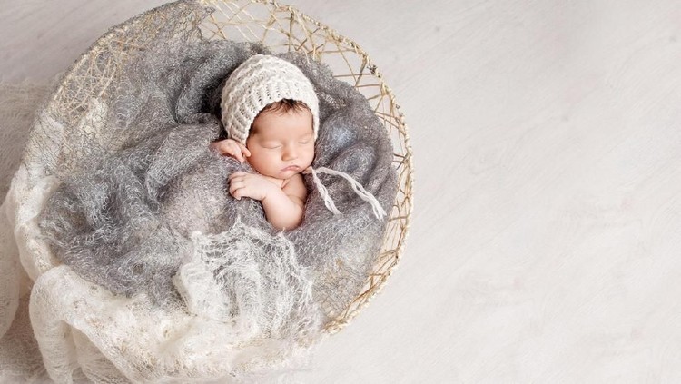 Beautiful little newborn baby 2 weeks sleeping in a basket with knitted plaid. Portrait of pretty  newborn baby. Copy space