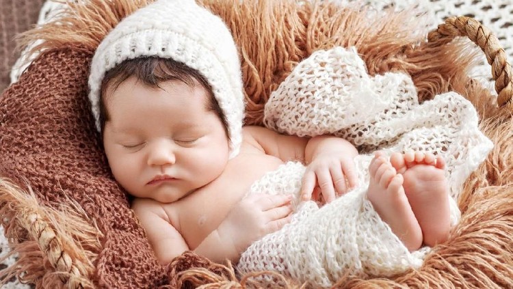 1142984829 Beautiful little newborn baby 2 weeks sleeping in a basket with knitted plaid. Portrait of pretty newborn baby. Copy space