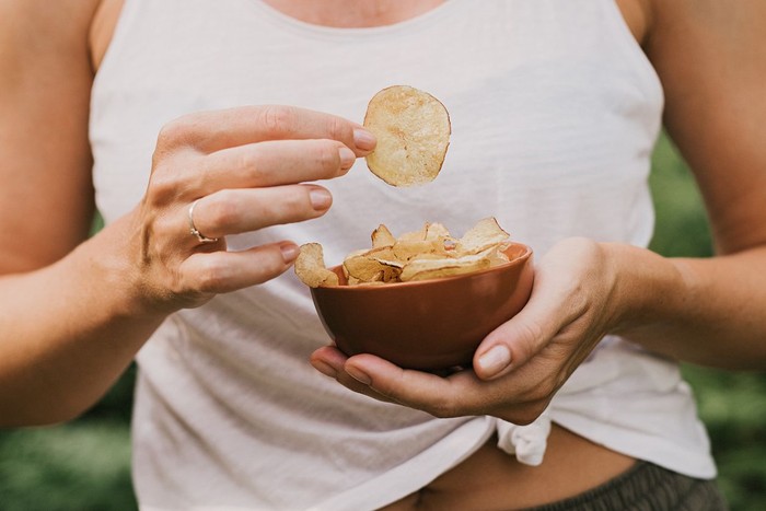 Woman eating chips snacks, close up of hands
Photo taken in summer in sunlight outdoors